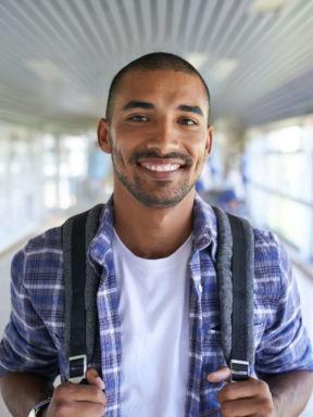 a student smiles for a portrait with his backpack