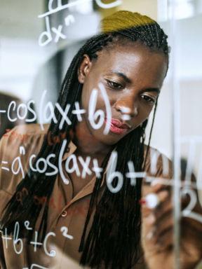 a student uses a glass wall to solve a mathematical equation