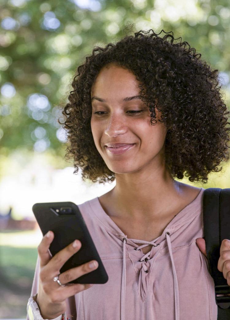a female student looks at her phone outdoors