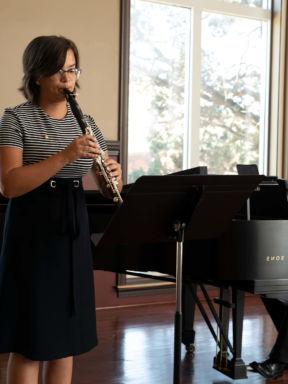 A woman playing the clarinet at a music recital
